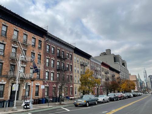 een stadsstraat met auto's geparkeerd voor gebouwen bij Room in a 2 Bedrooms apt. 10 minutes to Time Square! in West New York