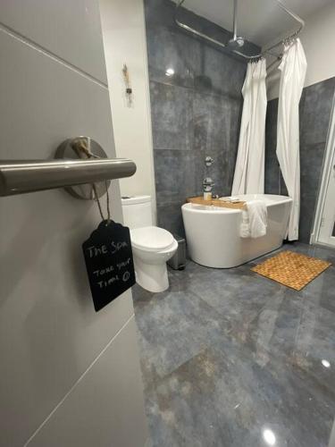 a bathroom with a tub and a toilet and a sink at Modern pool home on the lake near Hardrock FLL airport in Davie