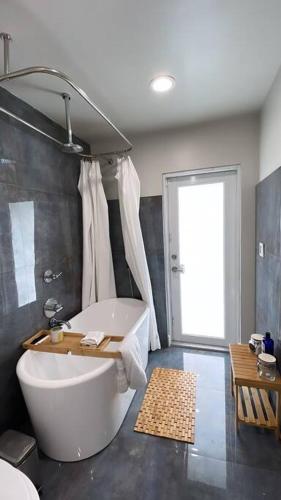 a bathroom with a large white tub in a room at Modern pool home on the lake near Hardrock FLL airport in Davie