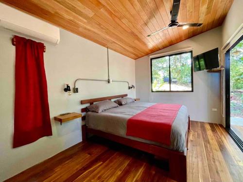 een slaapkamer met een groot bed en een rode deken bij Industrial Studio with private Jacuzzi in Uvita