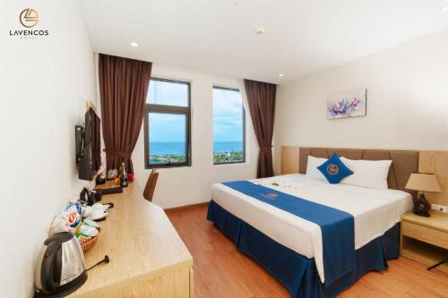 una camera d'albergo con un grande letto e finestre di Lavencos Hotel Da Nang a Da Nang