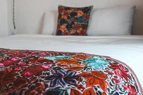 Kay Apartments Isla Mujeres في إيسلا موخيريس: سرير مع بطانية ملونة عليه مع وسادة