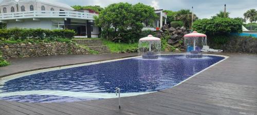 a swimming pool with two water fountains in a yard at Baishawan Marina B&B in Shimen