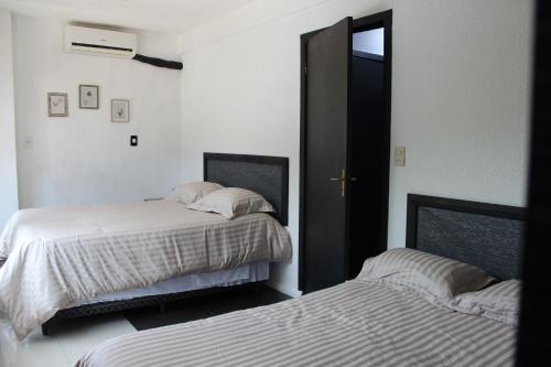1 dormitorio con 2 camas y puerta con espejo en Apartamento 80 O´H Aparthotel., en Ciudad del Este