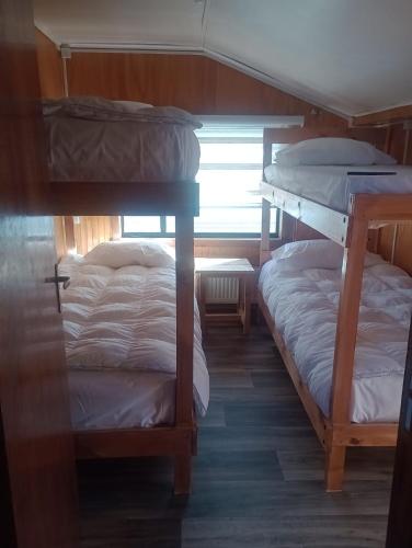 2 stapelbedden in een kamer met een raam bij Isla yu backpacker in Puerto Natales