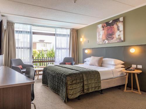 um quarto de hotel com uma cama e uma varanda em Auckland Rose Park Hotel em Auckland