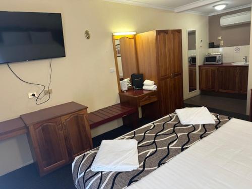 a hotel room with two beds and a flat screen tv at City Centre Motel Kempsey in Kempsey
