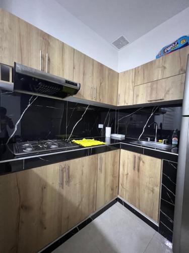 a kitchen with wooden cabinets and a stove top oven at Linda casa en el espinal tolima in Espinal