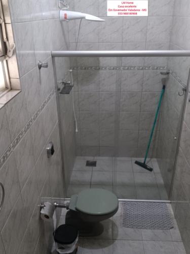 La salle de bains est pourvue d'une douche et de toilettes vertes. dans l'établissement LM Home, à Governador Valadares