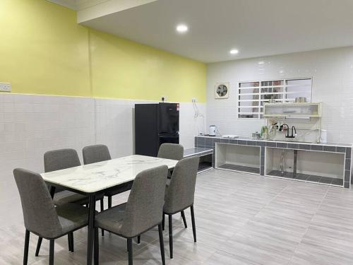 a dining room with a table and chairs and a kitchen at Happi Homestay@Taman Saga in Bentong
