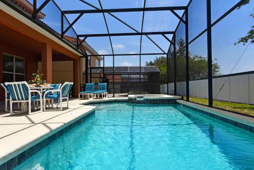a swimming pool with chairs and a table on a patio at Family Friendly Home, South-facing Pool,Spa, Gated Resort near Disney -928 in Davenport