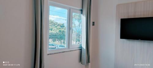 a room with a window and a flat screen tv at Pousada Roberto Monteiro - Frente Mar in Florianópolis
