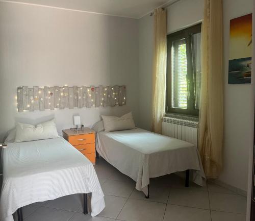 a bedroom with two beds and a window with lights at Villa Palummo - Stunning Sea View Zambrone, Calabria in Zambrone