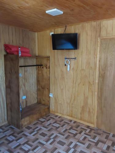 Zimmer mit einer Wand, einem TV und einer Tür in der Unterkunft Suit Victoria (2 camas singles) in Hanga Roa