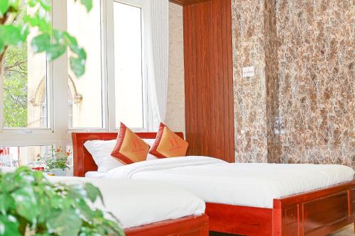 two beds in a room with two windows at H Flower Hotel and Villa Đà Lạt in Da Lat