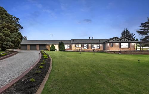 a house with a grass yard in front of a building at Mountain Culture Farm Stay - pet friendly in Kanimbla