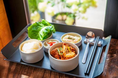 a tray with four bowls of food on a table at Parkavenue Guesthouse in Seoul