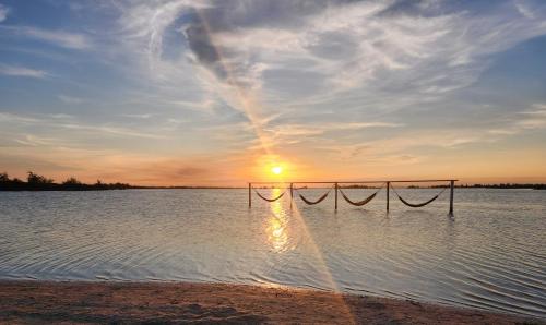 um pôr-do-sol sobre uma massa de água com uma rede em Golden Lake RJ - Lindo como um Resort! em Arraial do Cabo