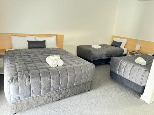 a bedroom with two beds and a ottoman at Twin City Motor Inn in Wodonga