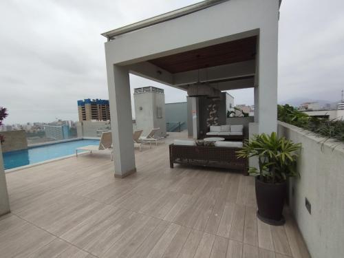 a patio with a couch and chairs on a roof at Hermoso condominio estilo Urban in Lima