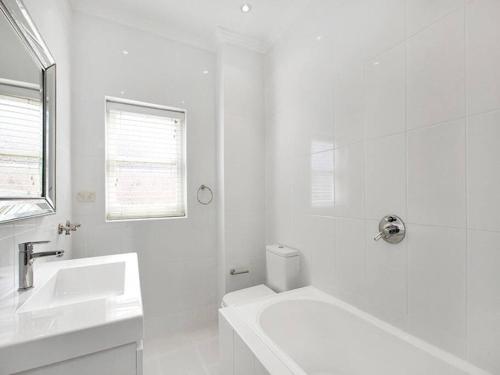 Baño blanco con lavabo y bañera en Stylish & Sunlit Bellevue Hill, en Sídney