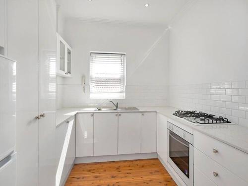 a white kitchen with a sink and a stove at Stylish & Sunlit Bellevue Hill in Sydney