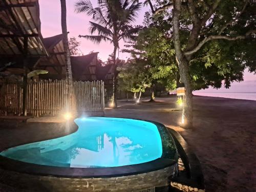 a swimming pool at night with a fountain at Beach House Penida in Nusa Penida