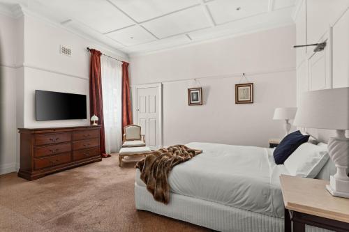 a white bedroom with a bed and a television at The Robertson Hotel in Robertson