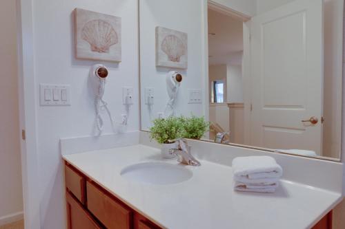 a white bathroom with a sink and a mirror at Summer Escape - Spacious 8BR Home with Private Pool! in Kissimmee