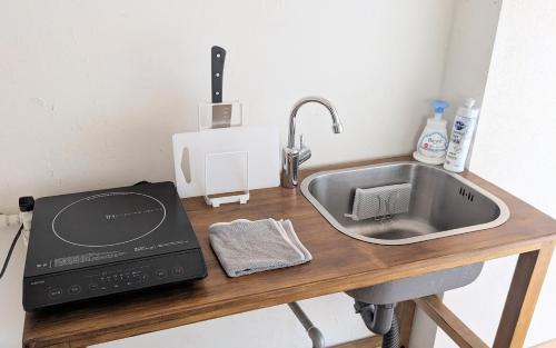 eine Küchentheke mit einer Spüle und einer Mikrowelle in der Unterkunft 1日1組限定の和室style心地よいコンドミニアム in Matsumoto