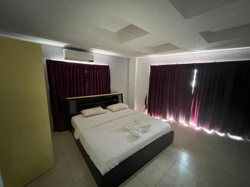 a bedroom with a white bed with red curtains at Beach&hills in Pattaya South