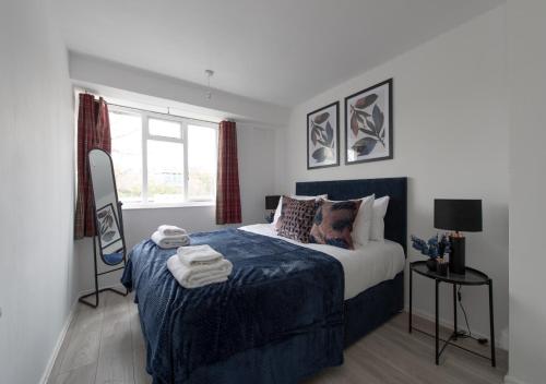 a bedroom with a bed with a blue blanket and a window at Prime London Location 3-Bed Flat in London