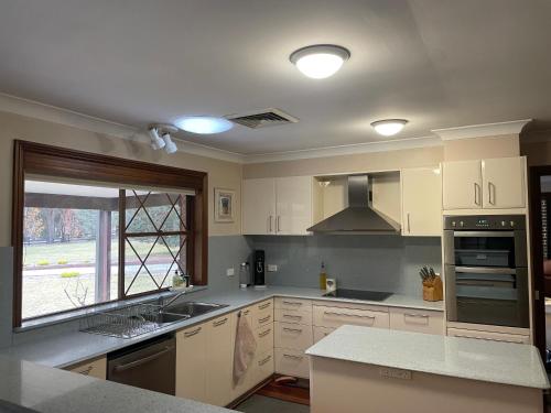 a kitchen with white cabinets and a sink and a window at Mountain Culture Farm Stay - pet friendly in Kanimbla