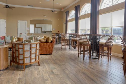 a living room with tables and chairs and windows at Summer Escape - Spacious 8BR Home with Private Pool! in Kissimmee
