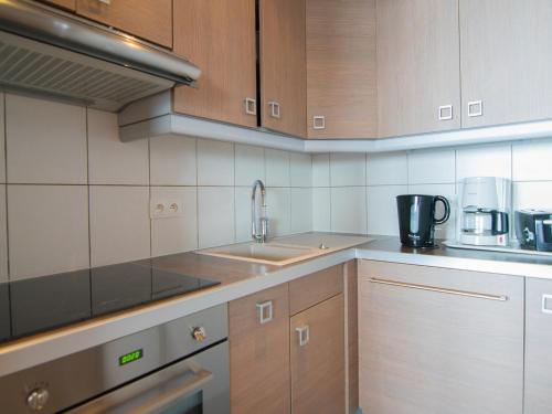 une cuisine avec des armoires en bois et un évier dans l'établissement 2 pièces sud/ouest proche pistes, WiFi, animaux admis - FR-1-449-118, à Tignes