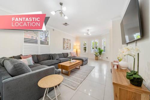 a living room with a gray couch and a tv at Petal and Bloom - 3BR Family CBD in Adelaide