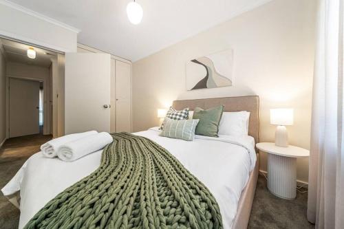 1 dormitorio con 1 cama grande con manta verde en Petal and Bloom - 3BR Family CBD en Bowden