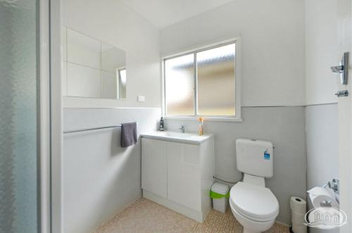 uma casa de banho branca com um WC e uma janela em Bluefin On Theresa em Portland