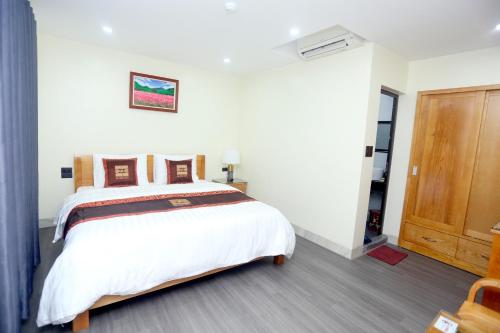 a bedroom with a large white bed and a wooden door at HOA CƯƠNG HOTEL 2 (HÀ GIANG) in Ha Giang