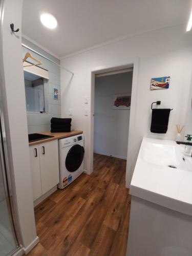 a kitchen with a sink and a washing machine at Anchor watch in Whangamata