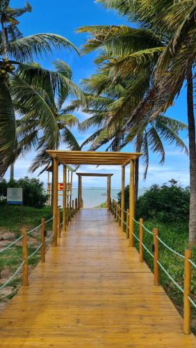 un paseo marítimo de madera que conduce a la playa con palmeras en Casa Flora Patacho en Pôrto de Pedras