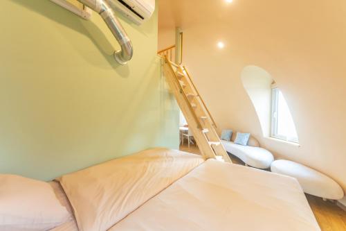 a small bedroom with a bed and a ladder at Cam Cam Dome House & SAUNA 豊岡海岸 in Minamiboso