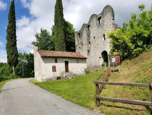 an old stone building on a hill next to a road at SIM residence in Maniago