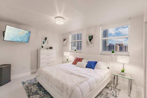 een witte slaapkamer met een bed en 2 ramen bij Upscale Brickell 2 bedroom with water views and free parking in Miami