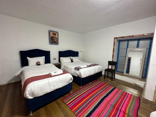 a bedroom with two beds and a rug at AITANA'S HOUSE - SAN BLAs in Cusco