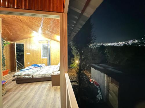 a room with a bed on a porch at night at TREE HOUSE BY THE CITY ESCAPE in Shimla