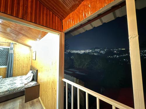 a room with a balcony with a large window at TREE HOUSE BY THE CITY ESCAPE in Shimla