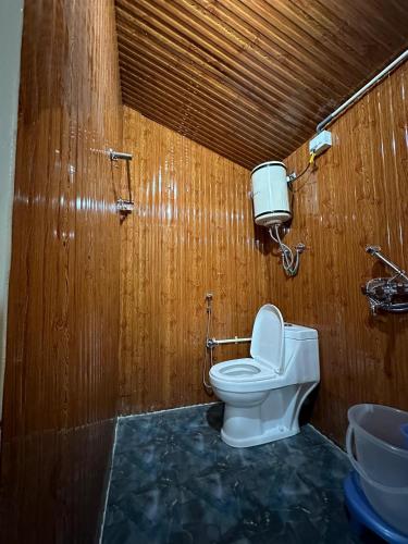 a bathroom with a toilet and a wooden wall at TREE HOUSE BY THE CITY ESCAPE in Shimla