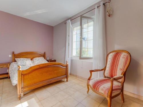 ein Schlafzimmer mit einem Bett, einem Stuhl und einem Fenster in der Unterkunft Villa with swimming pool in Sorgues in Sorgues