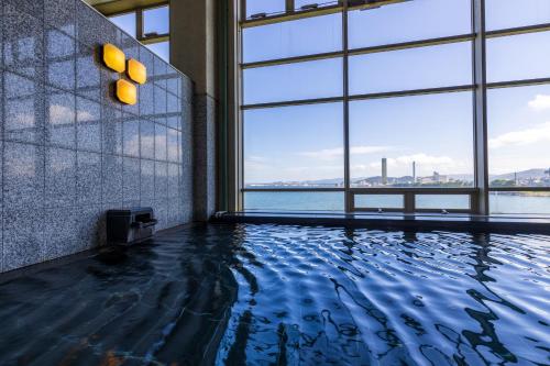 een zwembad met uitzicht op het water in een gebouw bij Okura Hotel Marugame in Marugame